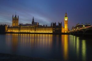 Night view of Big Ben and the Houses of Parliament illuminated, reflected in the Thames River, London.